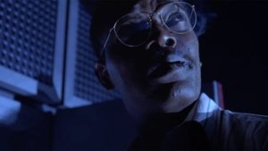 Samuel L. Jackson, as he appears in the original Jurassic Park movie. The scene is mostly dark. Jackson turns his head towards the camera, but looks at something offscreen. The cigarette in his mouth adds another meaning to his line.