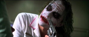 The Joker, as portrayed in The Dark Knight (2008), lets someone offscreen (Two-Face) point a gun to his face. He is dressed as a nurse in addition to his clown makeup.