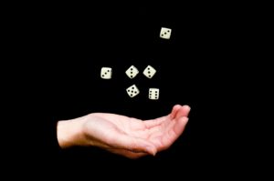 A public domain photo of a hand dossing six dice into the air. Courtesy of PublicDomainPictures.net.
