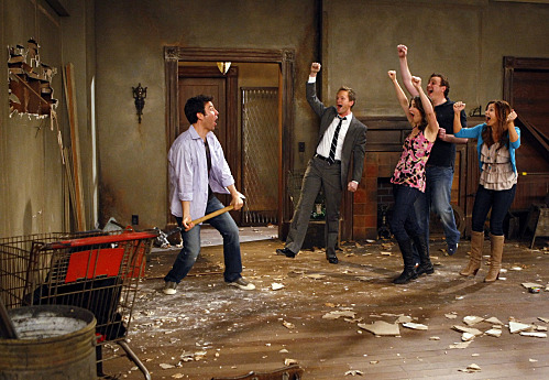 A scene from an episode of How I Met Your Mother where some characters cheer on another who is taking a sledgehammer to a wall (they are indoors).