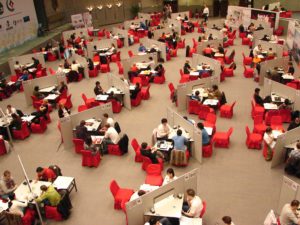 A large conference hall full of people sitting at tables playing bridge.